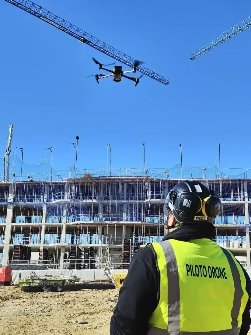 Piloto de dron trabajando junto a una grúa torre