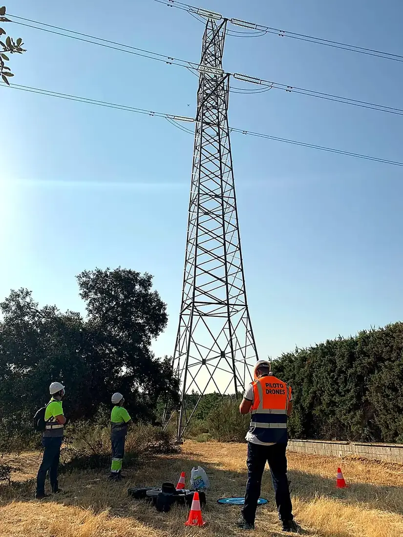 Equipo de pilotos inspeccionando una línea eléctrica de alta tensión con dron